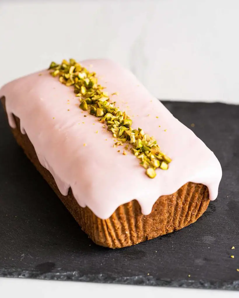 Baked eggless loaf cake with rose glaze and pistachio decoration