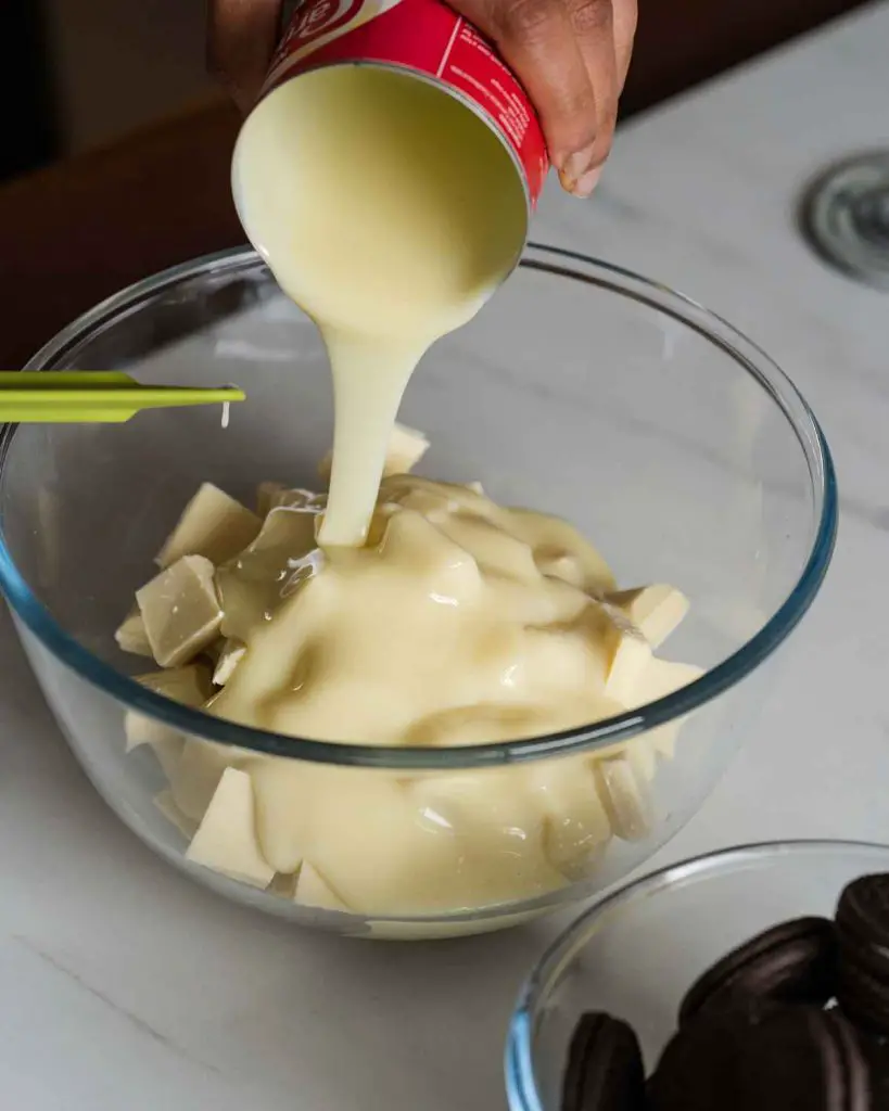Combining the condensed milk and white chocolate before melting. Recipe for Oreo fudge by movers and bakers