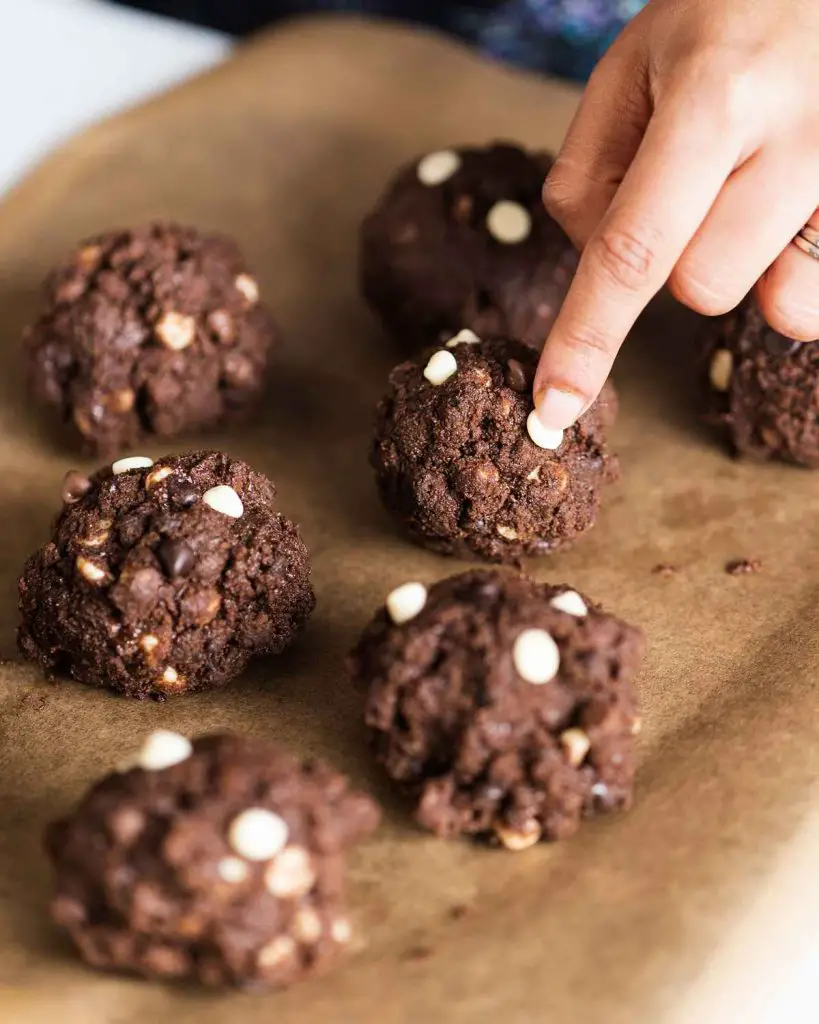 Adding extra choc chips on ultimate triple chocolate cookies before chilling. Recipe by movers and bakers