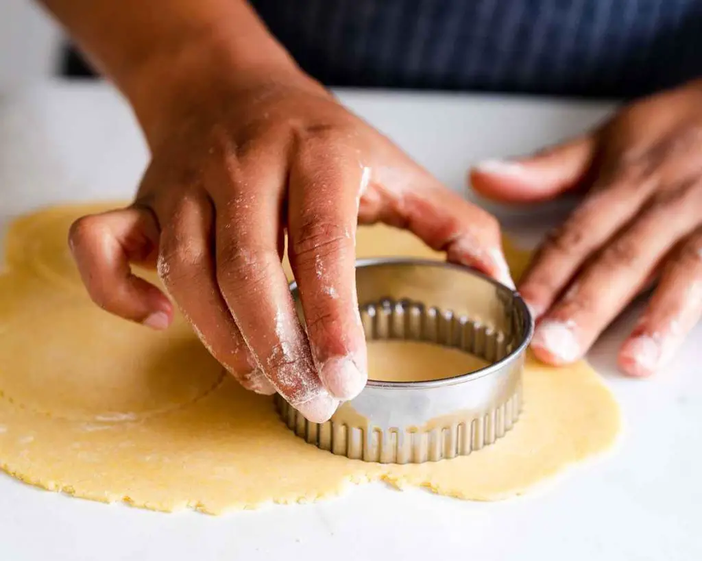 Cutting out the pastry before lining the tin with the pastry shells. Recipe by movers and bakers