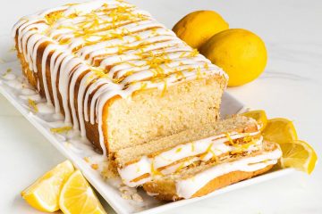 Vegan lemon drizzle loaf cake with two slices cut from it: light and fluffy and oh so lemony!