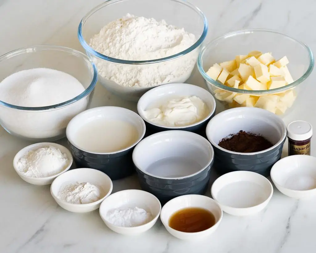Ingredients for the cake: unsalted butter, caster sugar, plain (all purpose) flour, cornflour (cornstarch), baking powder, bicarbonate of soda (baking soda), salt, cocoa powder, milk, yoghurt, water, vinegar and red food colouring. Recipe by movers and bakers