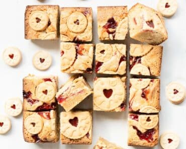Jammie dodger blondies. Yummy fudgy white chocolate blondies packed with beautiful jammie dodger biscuits and swirls of smooth raspberry jam. Recipe by movers and bakers