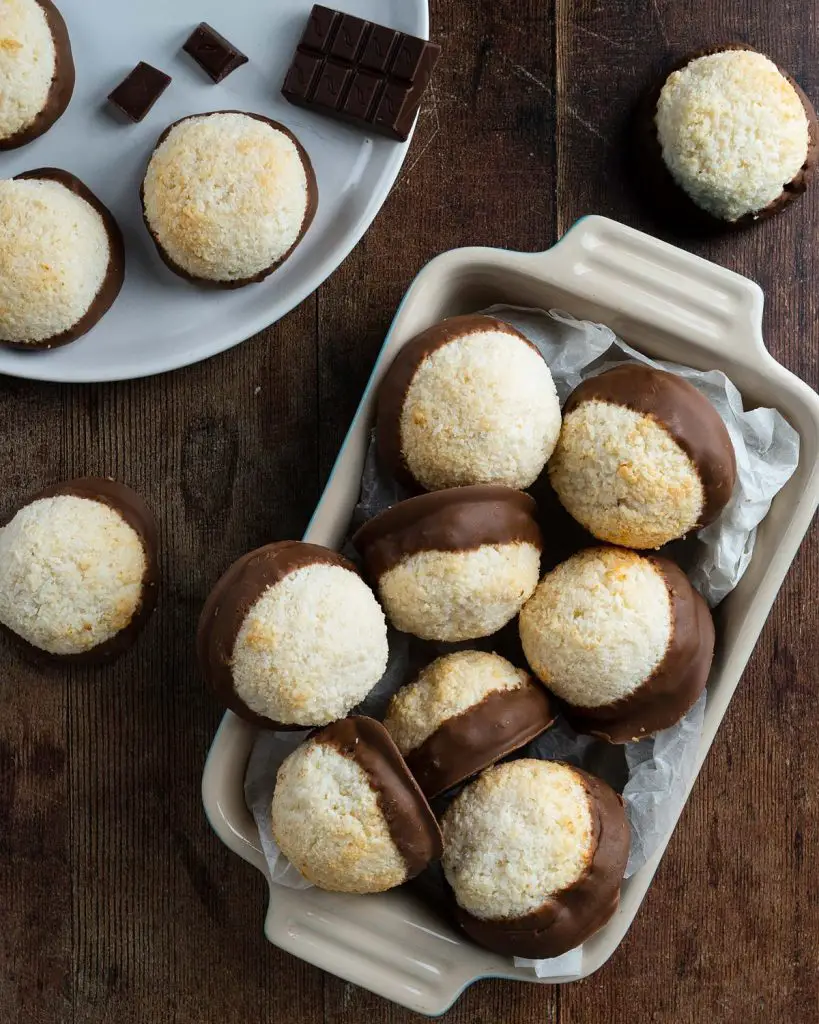 Coconut chocolate macaroons. These eggless macaroons use only three ingredients to make the most delicious macaroon cookies. These coconut cookies are crispy on the outside, wonderfully chewy in the middle and dipped in smooth milk chocolate. Just heavenly! Recipe by movers and bakers