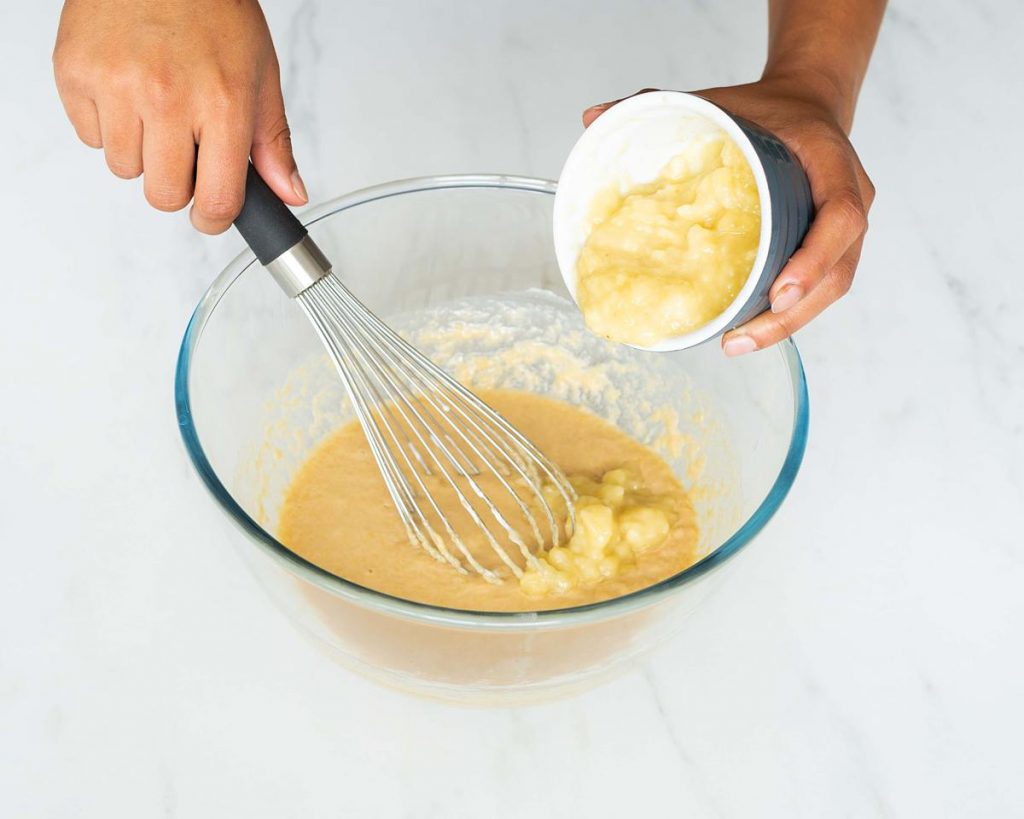 Adding in the mashed banana and mixing together. Recipe by movers and bakers