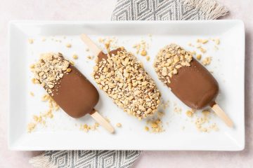 Peanut butter chocolate ice cream. Ice cream lollies made with creamy peanut butter ice cream dipped in a magic shell chocolate coating and topped with chopped peanuts. Recipe by movers and bakers