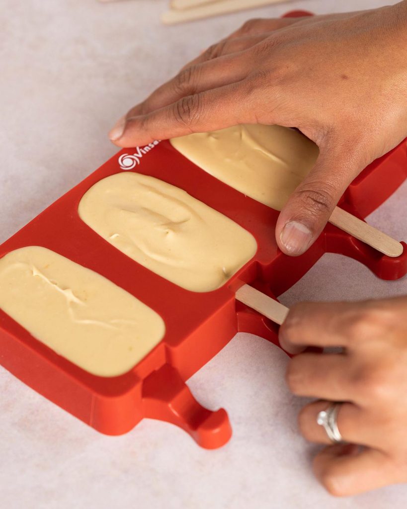 Gently push a wooden stick into each mould before freezing the ice creams. Recipe by movers and bakers