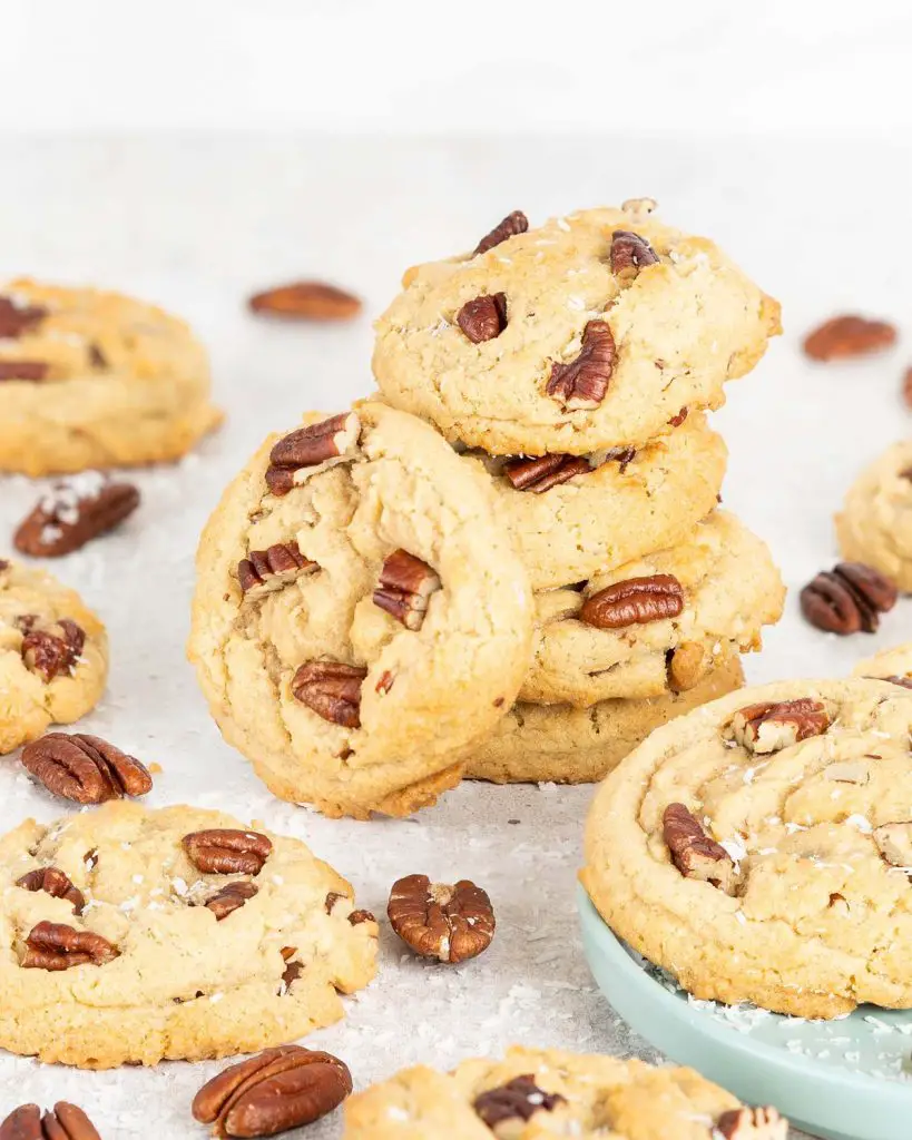 Beautiful coconut pecan cookies stacked, with one on its side. Recipe by movers and bakers