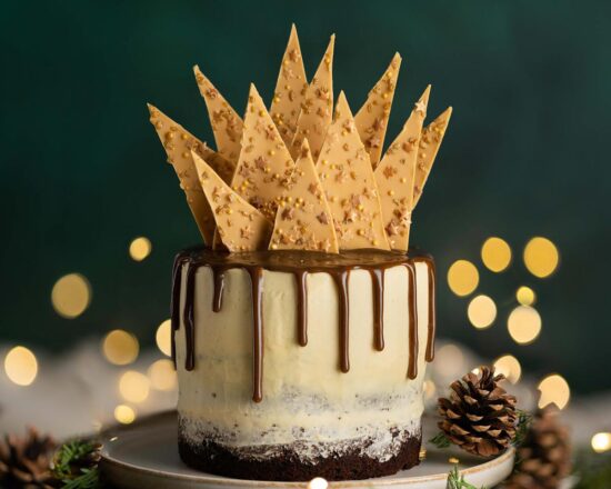 Sticky toffee pudding cake. Three layers of rich date sponge cake, sandwiched together with caramelised white chocolate buttercream, toffee drip and caramelised white chocolate shard topping. Recipe by movers and bakers