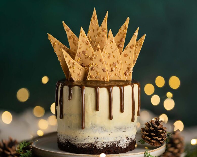 Sticky toffee pudding cake. Three layers of rich date sponge cake, sandwiched together with caramelised white chocolate buttercream, toffee drip and caramelised white chocolate shard topping. Recipe by movers and bakers