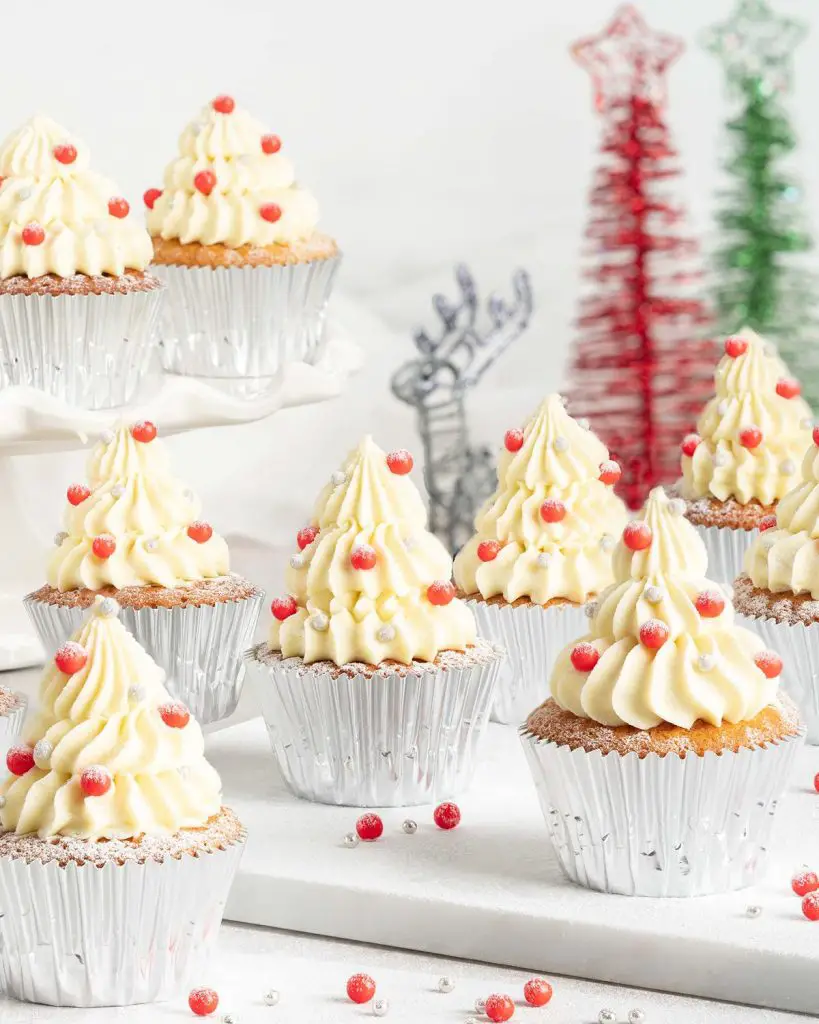 White chocolate Christmas tree cupcakes. Delicious light and fluffy white chocolate cupcakes topped with white chocolate buttercream Christmas trees and sprinkle decorations. Perfect for the festive season! Recipe by movers and bakers