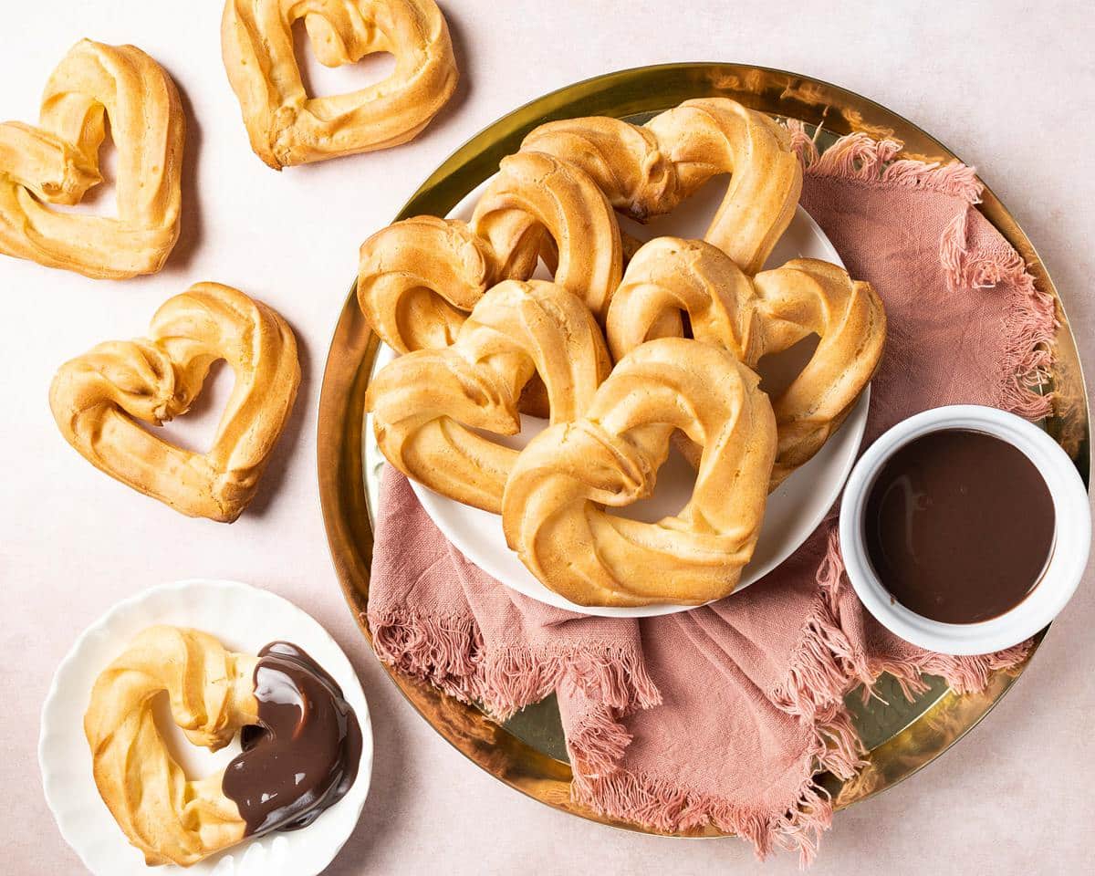 Churros with chocolate sauce. These heart shaped churros are a perfect Valentine's dessert, or just to share with loved ones any time! Churros served with a wonderful rich chocolate fudge sauce makes this an indulgent dessert everyone loves! Recipe by movers and bakers
