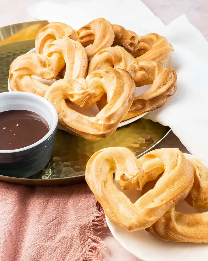 Churros with chocolate sauce. These heart shaped churros are a perfect Valentine's dessert, or just to share with loved ones any time! Churros served with a wonderful rich chocolate fudge sauce makes this an indulgent dessert everyone loves! Recipe by movers and bakers