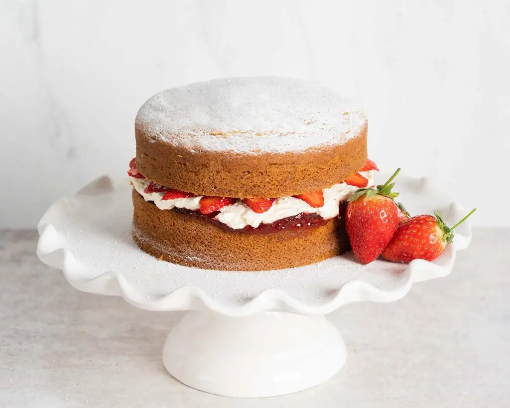 Victoria sponge cake. Two layers of light vanilla sponge cake sandwiched with strawberry jam, soft whipped cream and extra strawberries. Recipe by movers and bakers