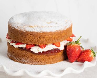 Victoria sponge cake. Two layers of light vanilla sponge cake sandwiched with strawberry jam, soft whipped cream and extra strawberries. Recipe by movers and bakers