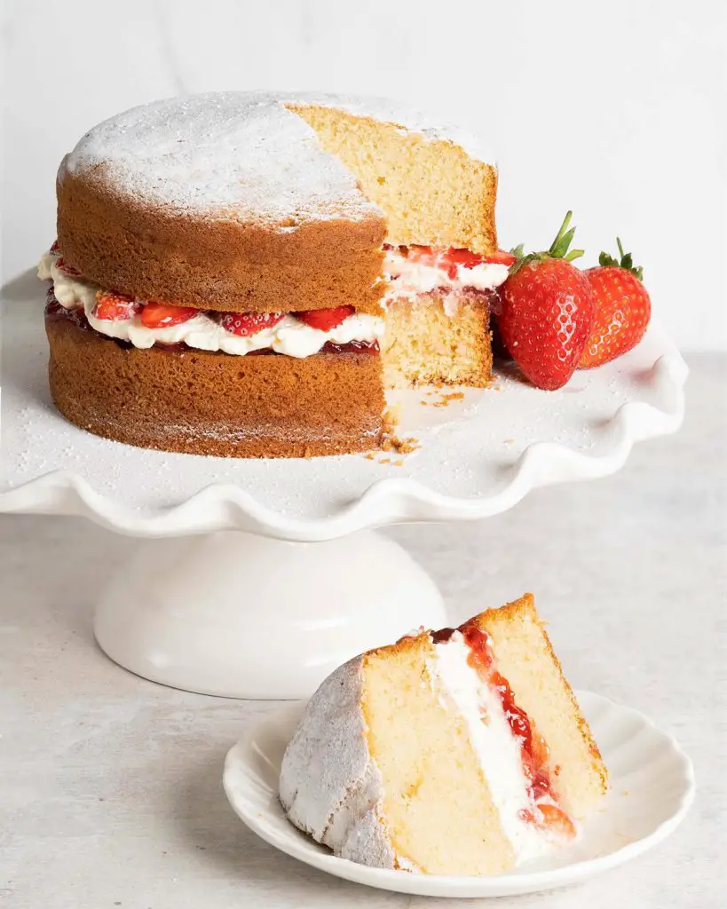 Victoria sponge cake. Two layers of light vanilla sponge cake sandwiched with strawberry jam, soft whipped cream and extra strawberries. Recipe by movers and bakers