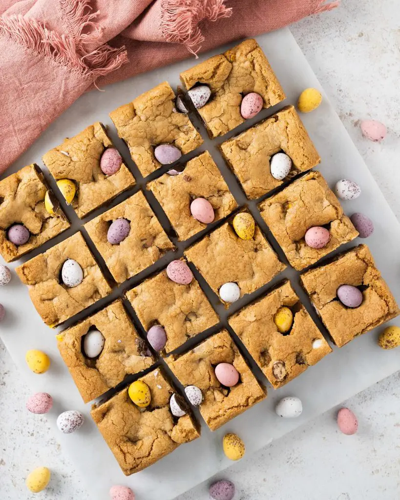 Mini egg cookie bars. Soft and chewy brown butter cookie bars packed with Cadburys mini eggs make this an Easter bake everyone will love! Recipe by movers and bakers