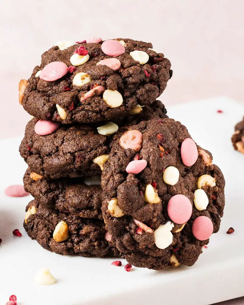 Raspberry ruby chocolate cookies. Deeply dark and chewy chocolate cookies packed with oodles of white and ruby chocolate chips and freeze dried raspberries. Recipe by movers and bakers