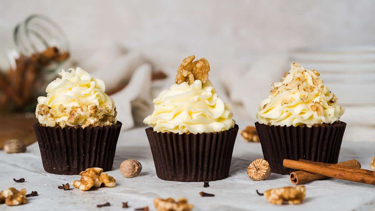 Carrot cake cupcakes. Moist and fluffy spiced carrot cake cupcakes with walnuts topped with a delicious tangy cream cheese frosting and decorated with walnuts. Recipe by movers and bakers