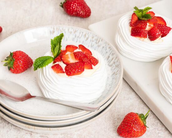 Eton mess mini pavlova nests. A perfect mash up for a summertime dessert, combining delicious pavlova with fresh strawberries and softly whipped cream. Recipe by movers and bakers