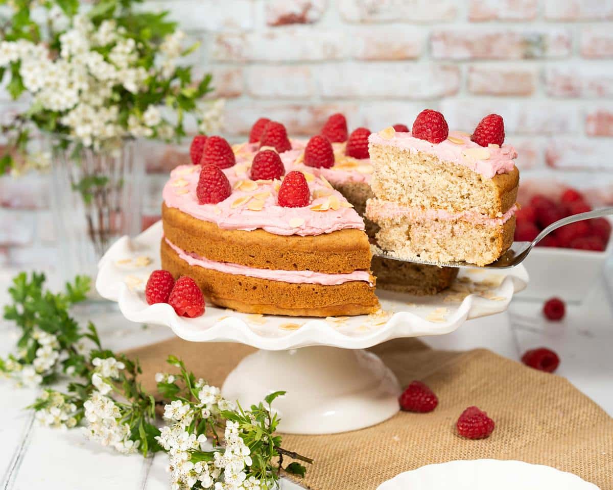 Raspberry almond cake. This vegan cake has moist almond cake layers, a fresh raspberry buttercream and lots of raspberries and flaked almonds to decorate. Recipe by movers and bakers