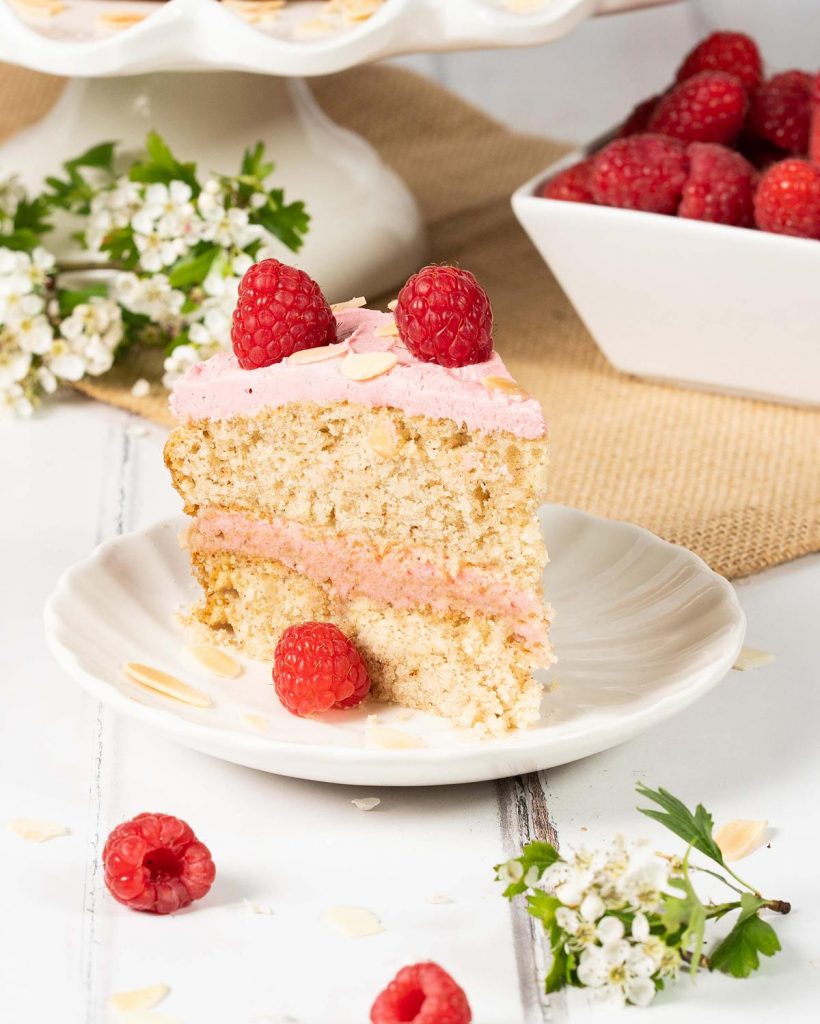 Raspberry almond cake. This vegan cake has moist almond cake layers, a fresh raspberry buttercream and lots of raspberries and flaked almonds to decorate. Recipe by movers and bakers