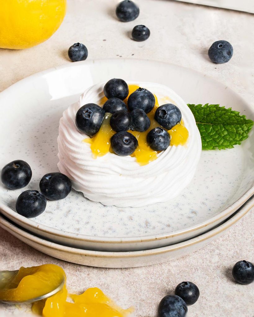 Lemon blueberry mini pavlova nests. Melt in your mouth meringue, soft whipped cream, lemon curd and plenty of blueberries make this a summertime dessert dream! Recipe by movers and bakers