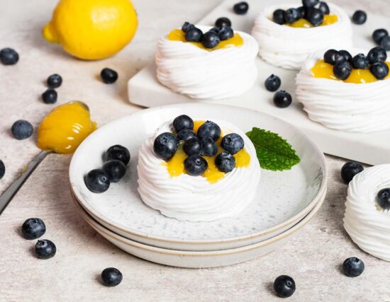 Lemon blueberry mini pavlova nests. Melt in your mouth meringue, soft whipped cream, lemon curd and plenty of blueberries make this a summertime dessert dream! Recipe by movers and bakers