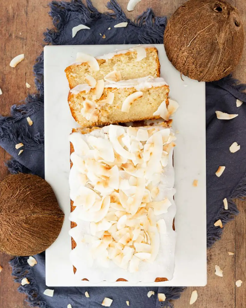 Vegan coconut cake. A light, fluffy and moist coconut cake, drizzled in a glorious coconut glaze and topped with toasted coconut shavings. Coconut tropical heaven! Recipe by movers and bakers