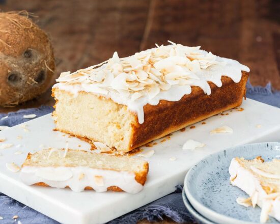 Vegan coconut cake. A light, fluffy and moist coconut cake, drizzled in a glorious coconut glaze and topped with toasted coconut shavings. Coconut tropical heaven! Recipe by movers and bakers