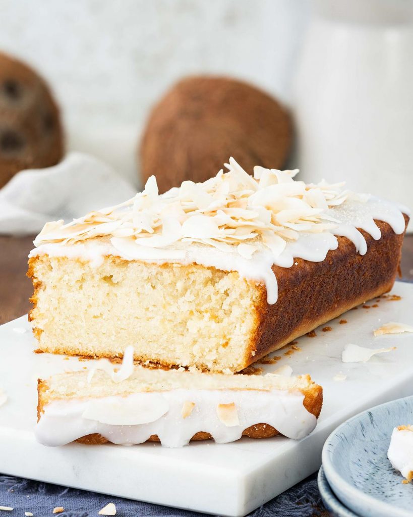 Vegan coconut cake. A light, fluffy and moist coconut cake, drizzled in a glorious coconut glaze and topped with toasted coconut shavings. Coconut tropical heaven! Recipe by movers and bakers