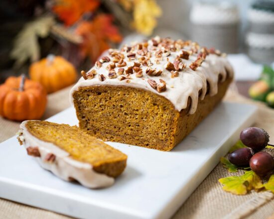 My pumpkin spice loaf cake is moist and delicate, gently spiced with warm pumpkin spice and topped with an irresistible maple spiced glaze and pecan pieces. Recipe by movers and bakers