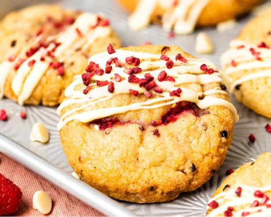 My wonderfully soft and chewy raspberry and white chocolate cookies are packed with lots of delicious pops of flavour, and topped with an extra pretty drizzle of white chocolate and freeze dried raspberries! Recipe by movers and bakers