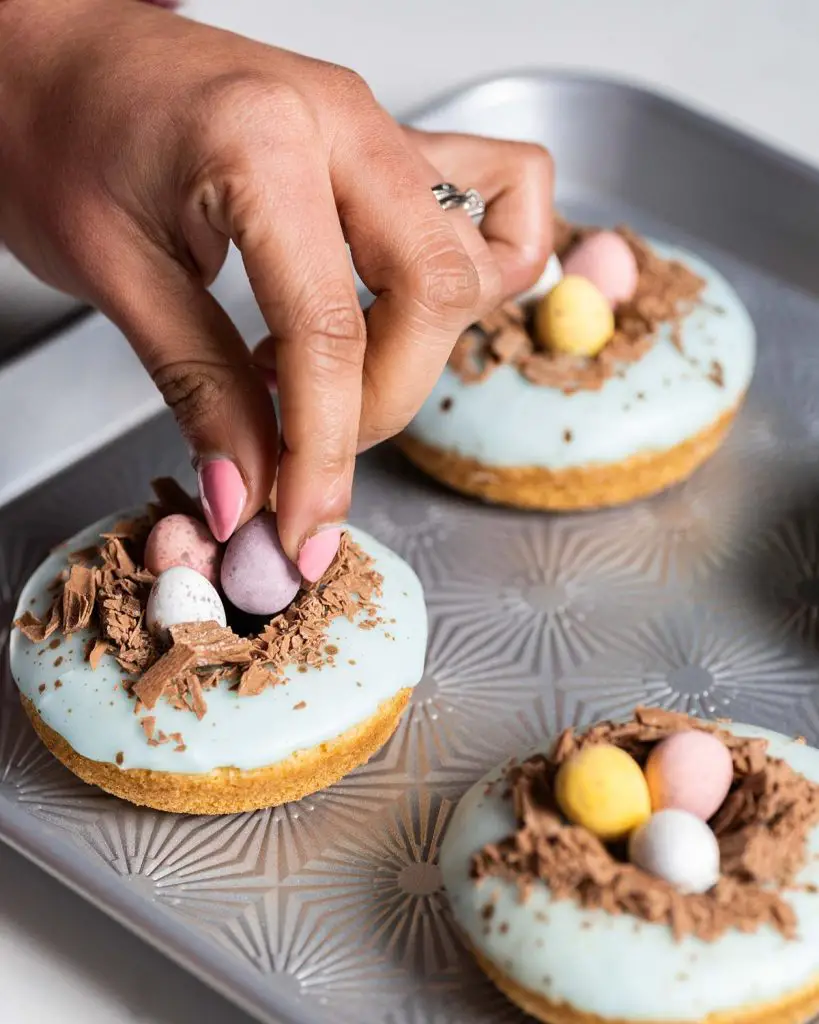 Adding the finishing touches of mini eggs into the nests. Recipe by movers and bakers