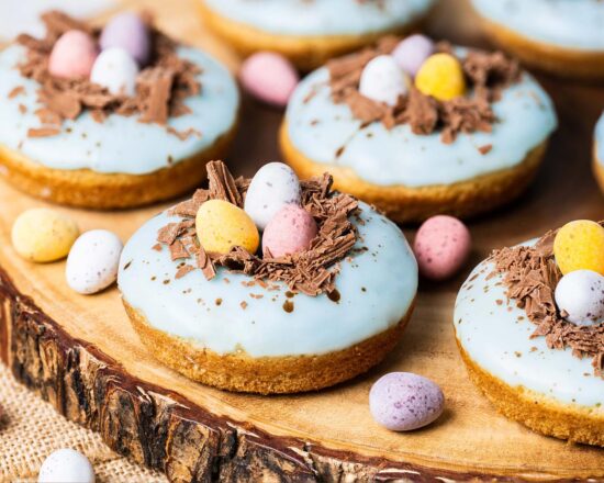Easter donuts. Light and fluffy vanilla donuts, topped with a duck egg speckled vanilla glaze, a chocolate nest and delicious mini eggs. The perfect Easter treat! Recipe by movers and bakers