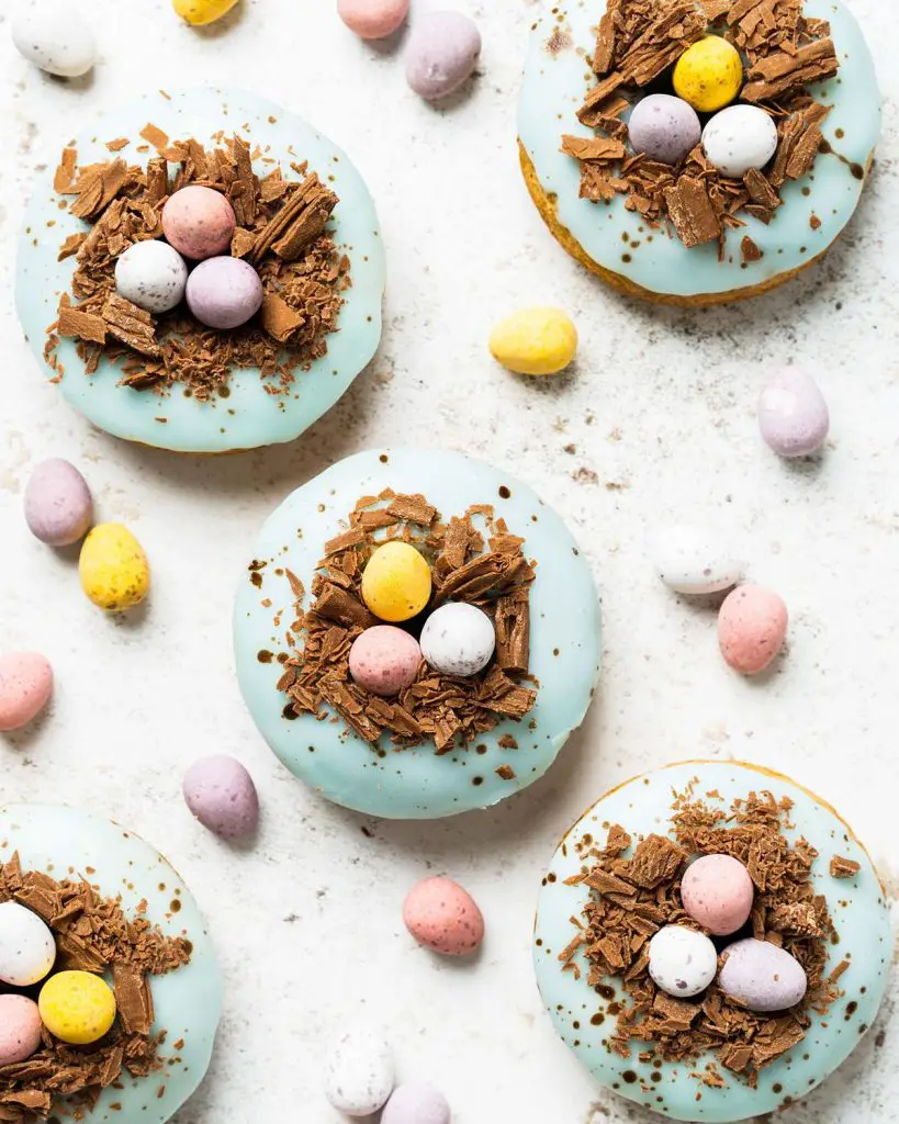 Easter donuts. Light and fluffy vanilla donuts, topped with a duck egg speckled vanilla glaze, a chocolate nest and delicious mini eggs. The perfect Easter treat! Recipe by movers and bakers