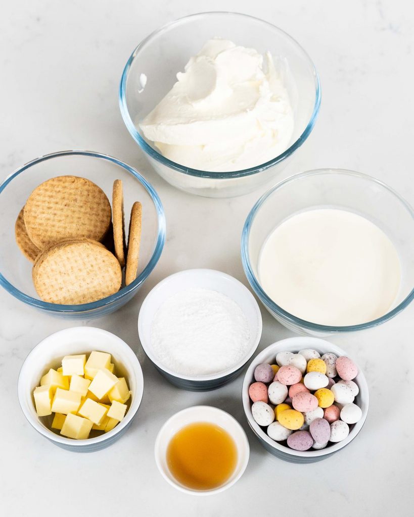 Ingredients required: digestive biscuits, unsalted butter, cream cheese, icing (powdered) sugar, vanilla, double (heavy) cream, milk chocolate and mini eggs. Recipe by movers and bakers
