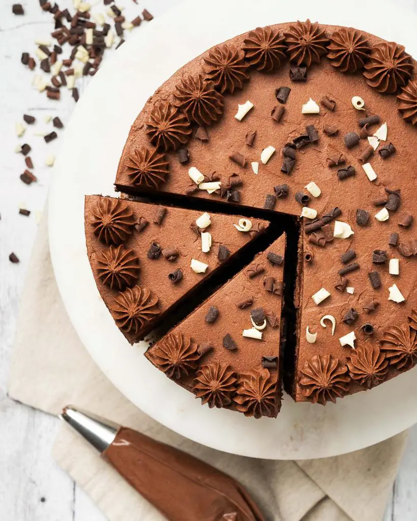 My eggless chocolate cake is light, moist and deeply chocolatey with a smooth chocolate buttercream and crowned with sprinkles. This cake is so good, no one will know it is egg free! Recipe by movers and bakers