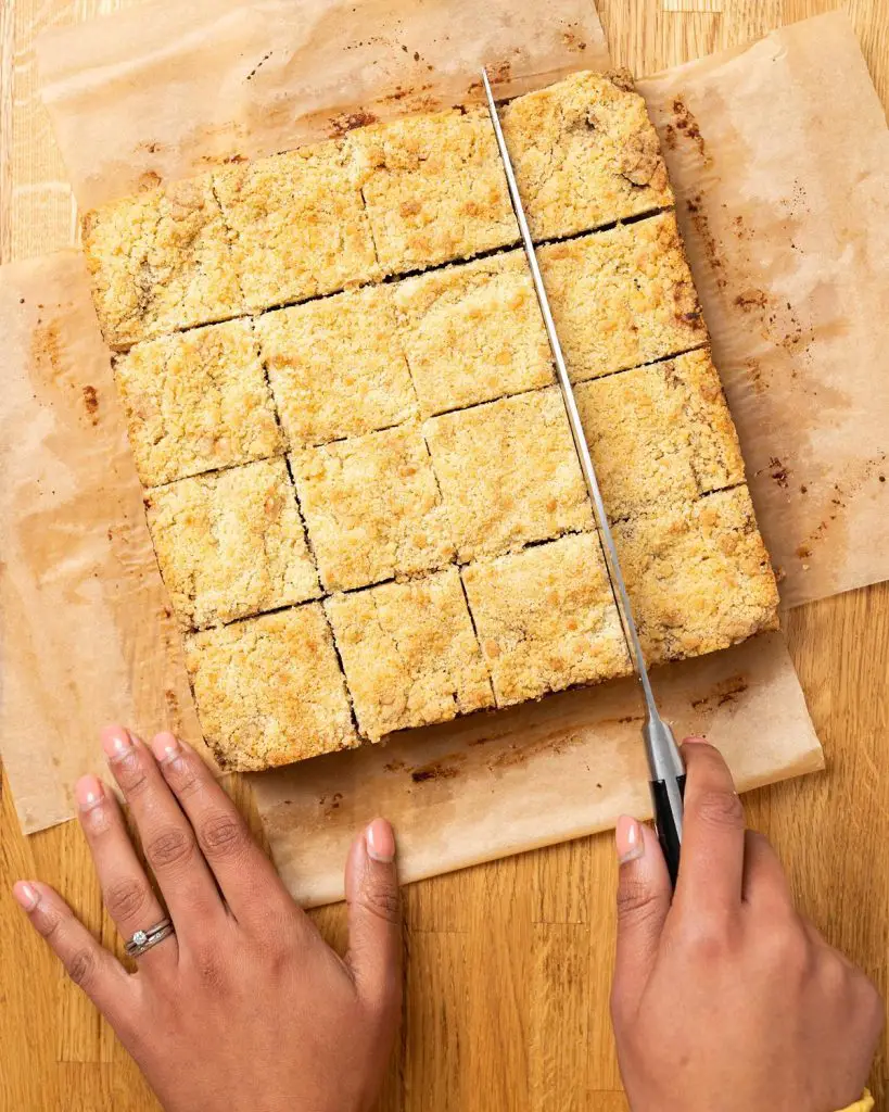 Cutting the cooled bars into squares before serving with a drizzle of caramel. Recipe by movers and bakers