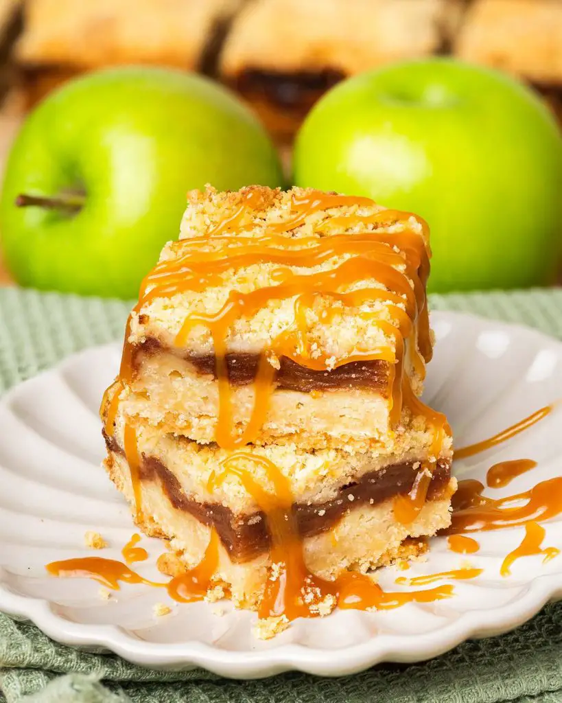 These caramel apple bars have a buttery shortbread base, a delectable cinnamon apple filling and crumbly topping, finished with a beautiful drizzle of caramel. Recipe by movers and bakers