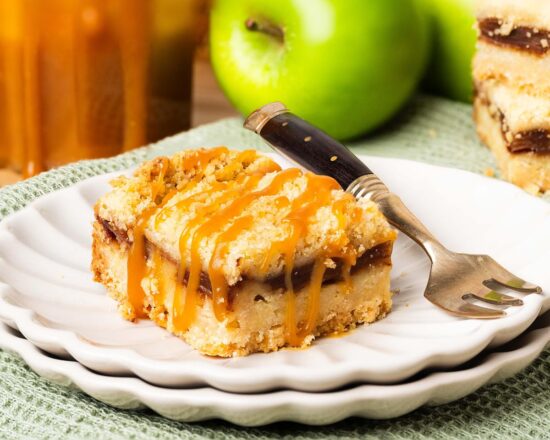 These caramel apple bars have a buttery shortbread base, a delectable cinnamon apple filling and crumbly topping, finished with a beautiful drizzle of caramel. Recipe by movers and bakers