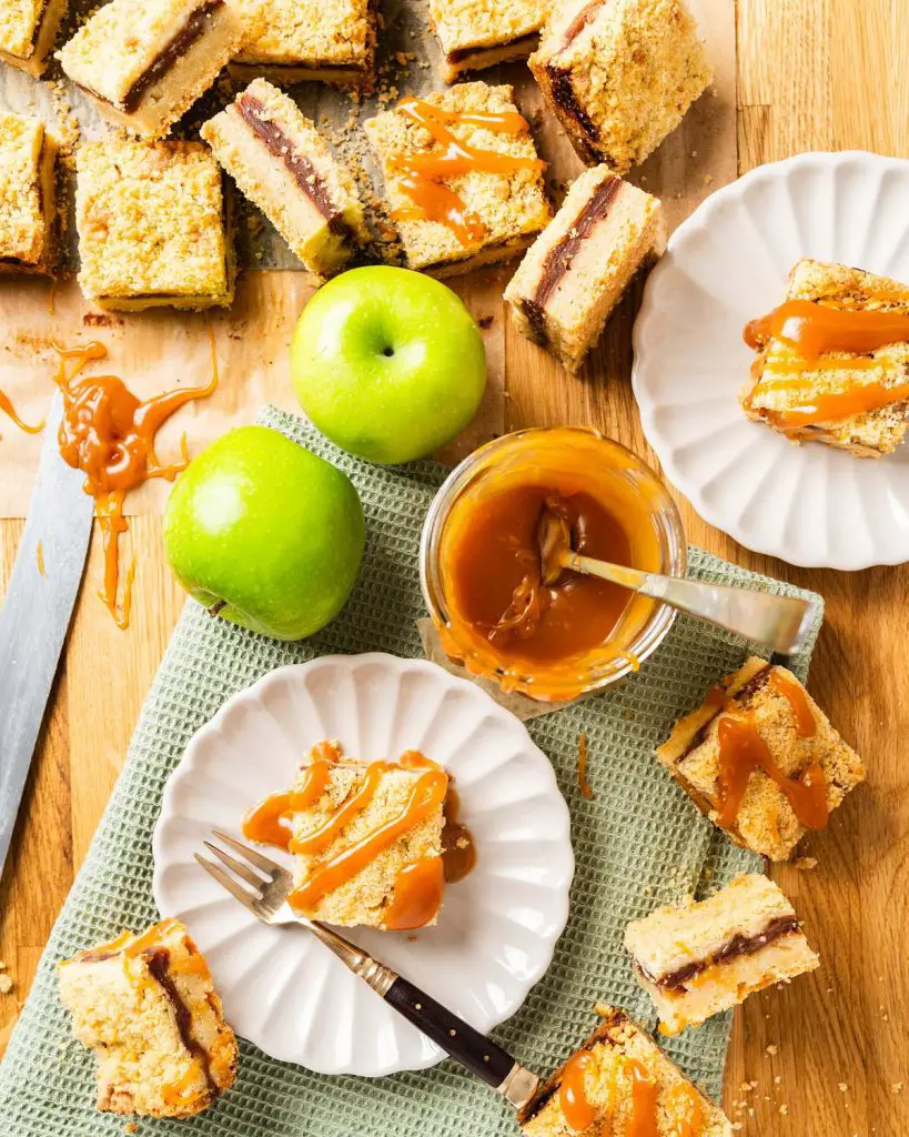 These caramel apple bars have a buttery shortbread base, a delectable cinnamon apple filling and crumbly topping, finished with a beautiful drizzle of caramel. Recipe by movers and bakers