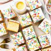 Go for gold with this nostalgic old school cake. A light vanilla traybake cake is topped with simple white icing and plenty of sprinkles. Serve with plenty of custard for the ultimate school dessert treat! Recipe by movers and bakers