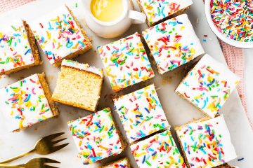 Go for gold with this nostalgic old school cake. A light vanilla traybake cake is topped with simple white icing and plenty of sprinkles. Serve with plenty of custard for the ultimate school dessert treat! Recipe by movers and bakers