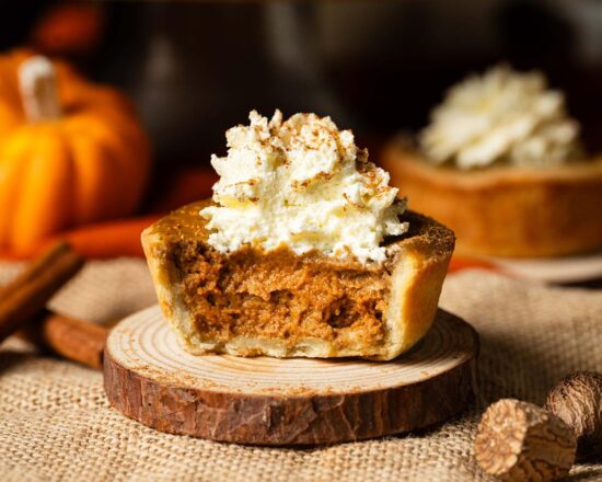 My mini pumpkin pies have a thin buttery shortcrust pastry shell and a deliciously autumnal pumpkin pie filling. Topped with a swirl of whipped cream and dusted with pumpkin spice, this is one dessert everyone will love! Recipe by movers and bakers