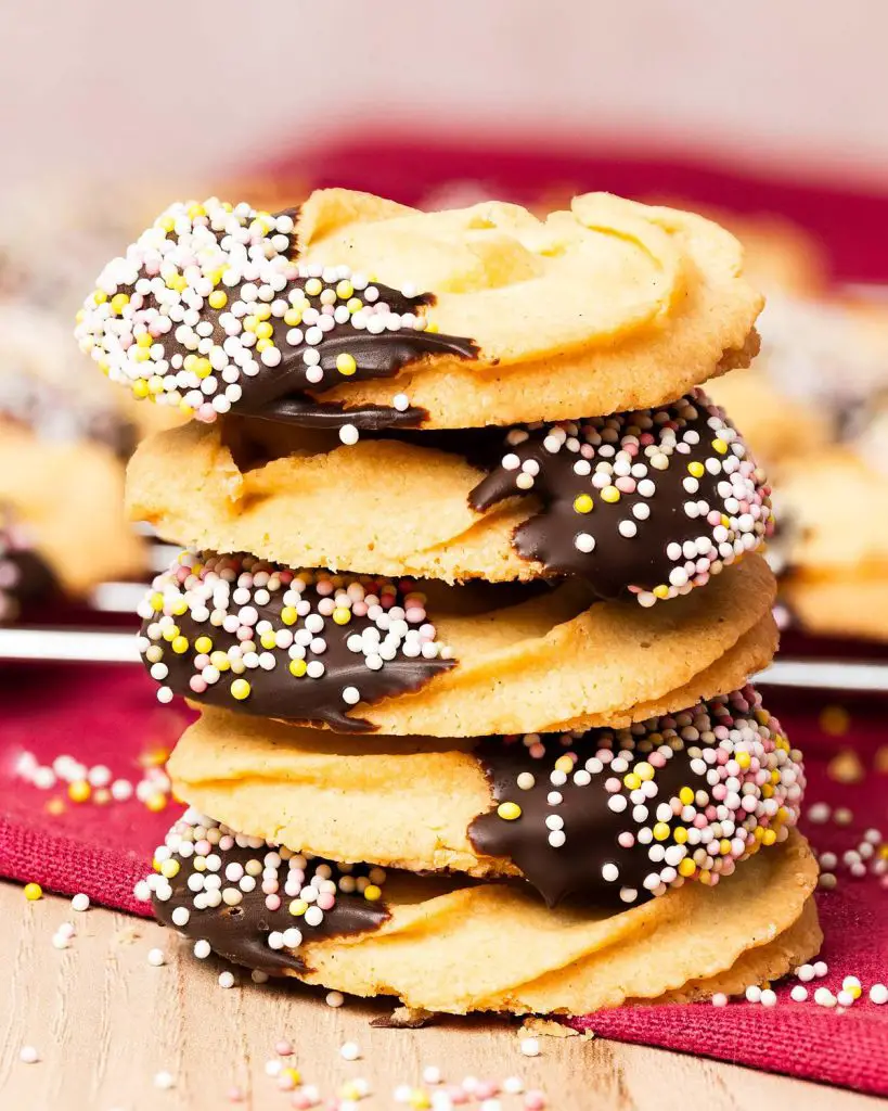 My chocolate dipped shortbread biscuits are a delightfully moreish tea time treat! Melt-in-your-mouth shortbread roses are partly dipped in chocolate and finished with colourful sprinkles for a bake everyone will love! Recipe by movers and bakers