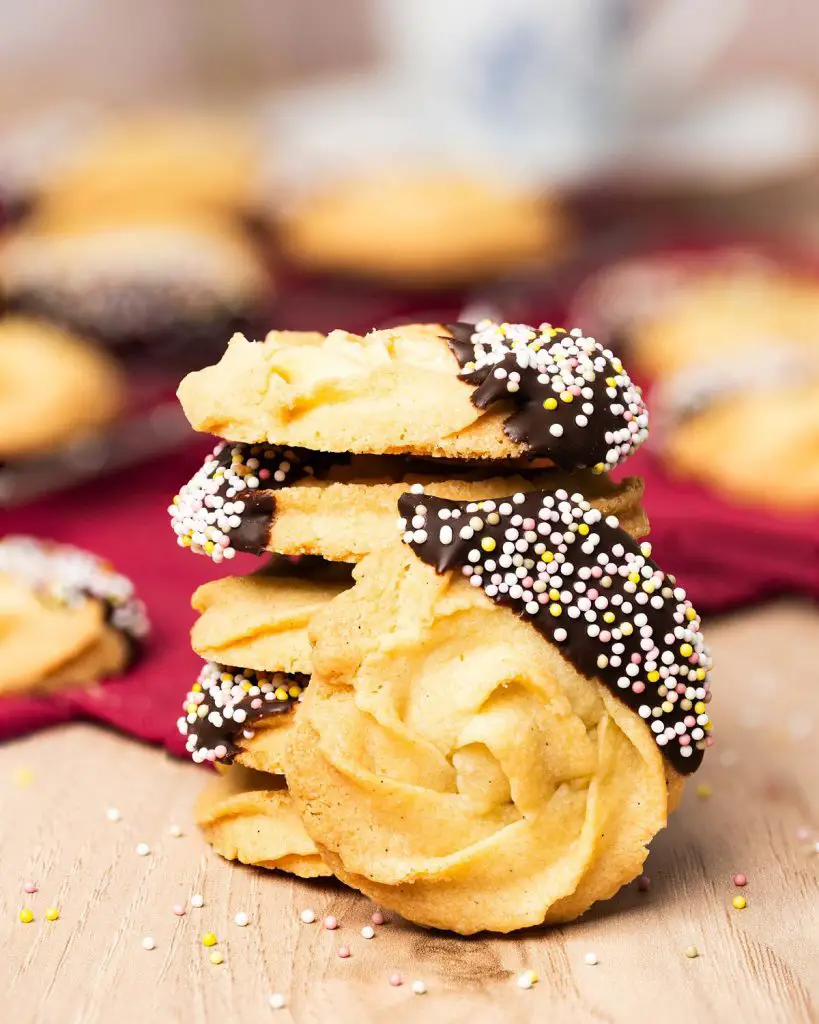 My chocolate dipped shortbread biscuits are a delightfully moreish tea time treat! Melt-in-your-mouth shortbread roses are partly dipped in chocolate and finished with colourful sprinkles for a bake everyone will love! Recipe by movers and bakers