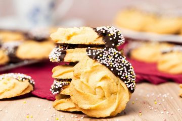 My chocolate dipped shortbread biscuits are a delightfully moreish tea time treat! Melt-in-your-mouth shortbread roses are partly dipped in chocolate and finished with colourful sprinkles for a bake everyone will love! Recipe by movers and bakers