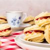 Viennese whirls are a delightful British sandwich biscuit! Two buttery piped shortbread biscuits are filled with soft vanilla buttercream and raspberry jam, making the perfect tea time treat! Recipe by movers and bakers