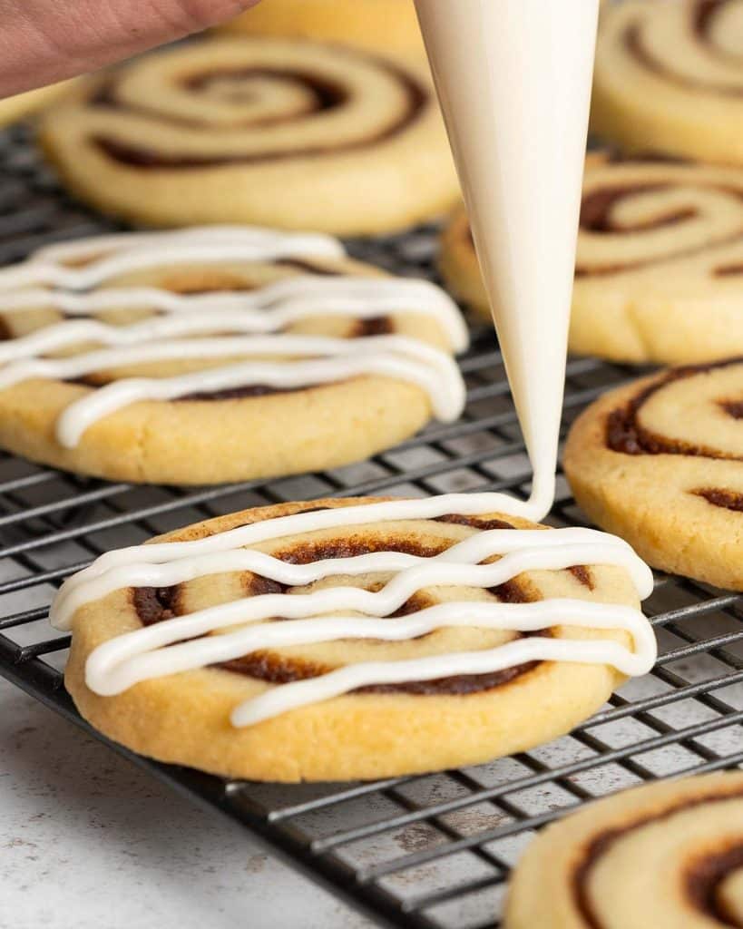 Piping on the cream cheese glaze before leaving to set. Recipe by movers and bakers